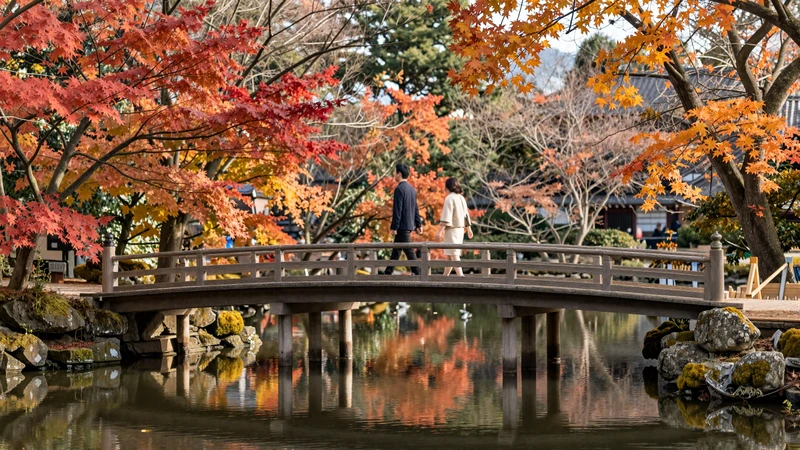 Autumn maple trees reflecting in a calm Kyoto temple pond with traditional wooden bridge for couples visiting Japan